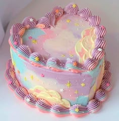 a heart shaped cake with pastel icing and stars on the top is sitting on a white surface