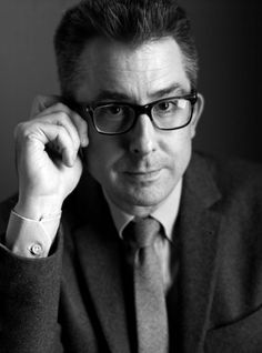 black and white photograph of a man in suit and tie posing for the camera with his hand on his head