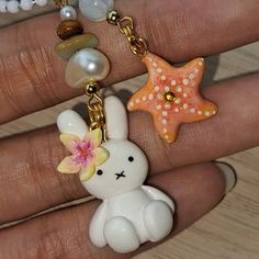 a hand holding a keychain with an animal and starfish charm on it
