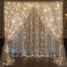 a white curtain with lights hanging from it's sides and sheer curtains on the side