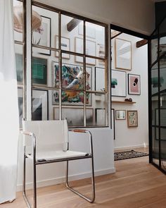 a white chair sitting in front of a glass wall with pictures on it's sides