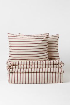 two pillows sitting on top of each other in front of a white background with red and black stripes