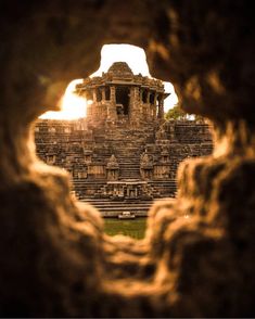 an ancient building is seen through a hole in the rock