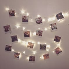 several polaroid pictures are hung on a string with fairy lights strung around them and hanging from the wall