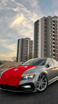 a red and silver car parked in front of tall buildings