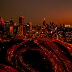an aerial view of a city at night with many cars on the road and buildings in the background