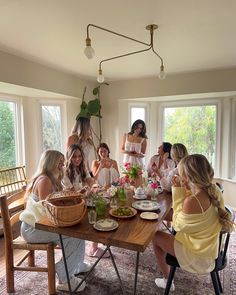 a group of women sitting around a table with food and drinks in front of them