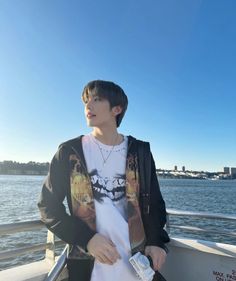 a man standing on top of a boat next to the ocean with his hands in his pockets