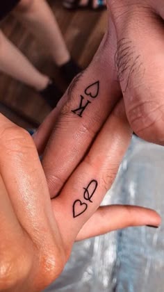 two people holding hands with tattoos on their fingers and the words love written on them