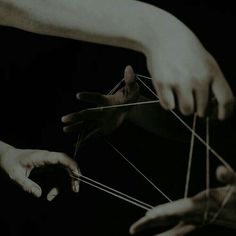 two hands are holding strings and pulling them apart from each other in black and white