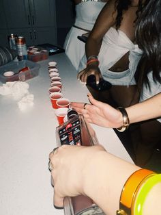 several people are sitting at a table with cups on it and one person is holding a cell phone