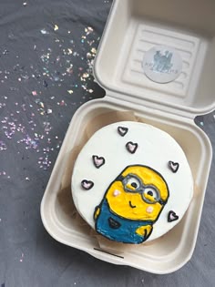 a decorated cake in the shape of a minion with hearts on it sitting in a foam container