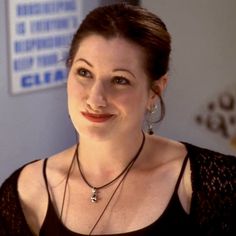 a woman wearing a black top and smiling at the camera with her hand on her hip