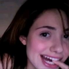 a close up of a person with a toothbrush in their mouth and one hand on her chin