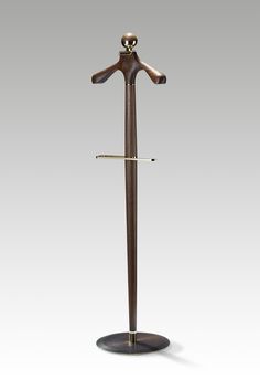 a wooden coat rack with two coats on it and an umbrella stand in the shape of a mannequin