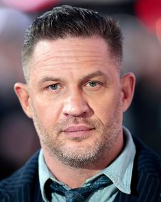 a close up of a person wearing a suit and tie with a serious look on his face