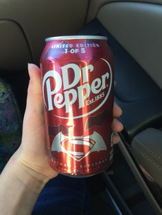 a person holding up a can of soda in the back seat of a car,