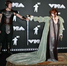 a man and woman dressed in medieval costumes holding swords while standing next to each other