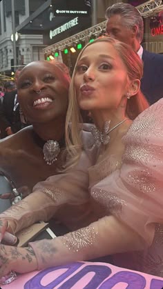 two women sitting next to each other in front of a crowd