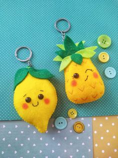 two stuffed fruit keychains sitting next to each other on a polka dot table