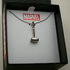 an open box with a necklace in it that has a hammer on the inside of it