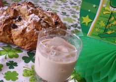 a glass filled with liquid next to a pastry on top of a green and white table cloth