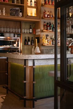 an empty bar with lots of bottles on the shelves and behind it is a tiled counter