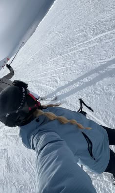 a person on skis is laying down in the snow with their back to the camera