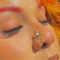 a close up of a woman's nose with an orange hair and piercing on it