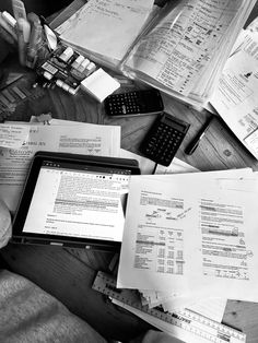 a person sitting at a desk with papers and calculator on it, in black and white