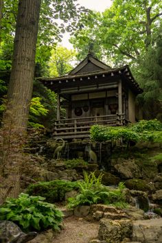 a small building in the middle of a forest with trees and rocks on both sides