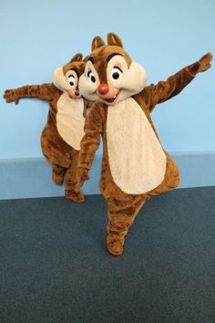 two brown chipmuns are dancing together on the floor in front of a blue wall