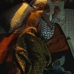 a man sleeping on top of a bed covered in blankets