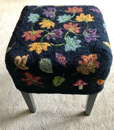 a foot stool with flowers on it in the middle of a carpeted flooring area