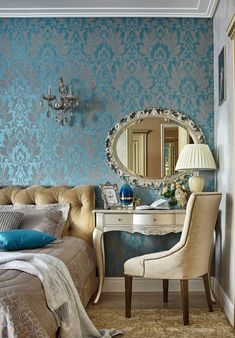 a bedroom with blue and white wallpaper, a chair, desk and mirror in it