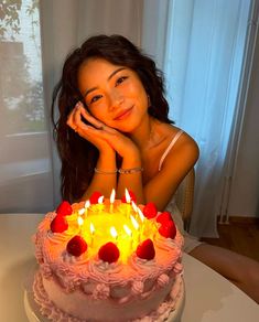 a woman sitting in front of a cake with lit candles