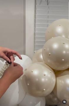 a woman is reaching for some white balloons
