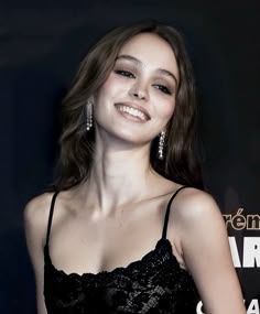 a woman in a black dress smiling at the camera