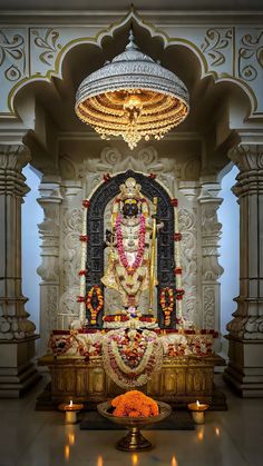 an idol in the middle of a room with candles around it and a chandelier hanging from the ceiling