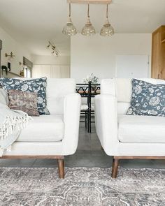 two white couches sitting next to each other on top of a carpeted floor