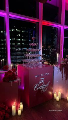 a table with candles and wine glasses on it in front of a window at night