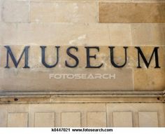 the museum sign on the side of an old building is black and has writing that reads museum