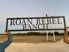 a man holding up a sign with the word roan rebbel ranch on it