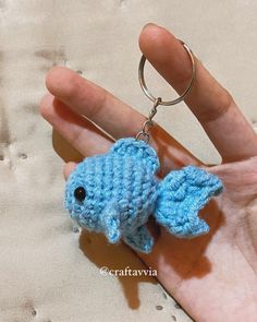 a small blue crocheted fish keychain in someone's hand