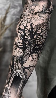 a man's arm with a tree and clock tattoo on the left side of his arm