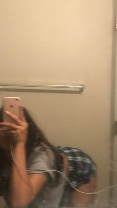 a woman taking a selfie in the mirror with her cell phone and headphones