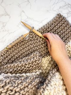 someone is crocheting a blanket with knitting needles