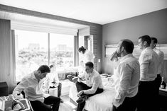a group of men standing around in a bedroom next to each other and one man sitting on a bed