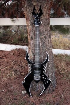 an electric guitar sitting on the ground next to a tree