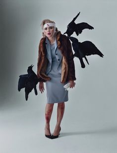 a woman in a dress and coat with birds on her shoulders